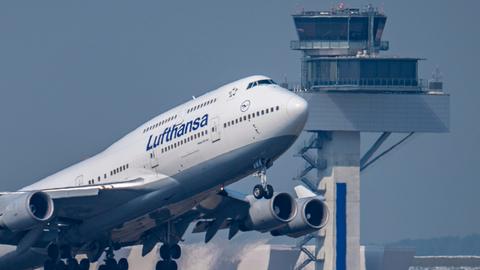 Lufthansa-Boeing 747 startet vor dem Tower des Frankfurter Flughafens.