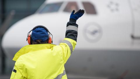 Ein Mitarbeiter hilft einem Flugzeug beim Einparken.