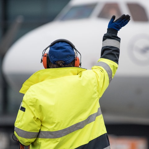 Ein Mitarbeiter hilft einem Flugzeug beim Einparken.