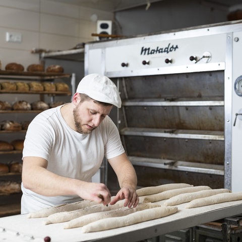 Nick Heinke, Mann mit Bart beim Baguette-Backen