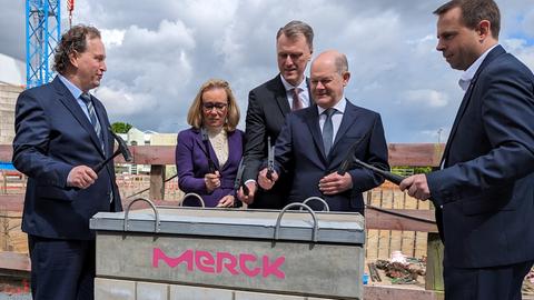 Bundeskanzler Olaf Scholz bei der Grundsteinlegung des neuen Merck-Forschungszentrums. In der Hand hält er einen Hammer. 