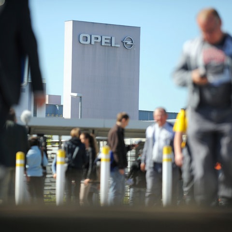 Menschen vor dem Opel-Turm in Rüsselsheim.