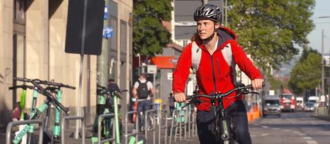 Eine Frau mit Helm auf dem Fahrrad im Stadtverkehr., 