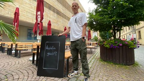 Auf einem Schild steht: "Aushilfen gesucht" für die Gastronomie. 