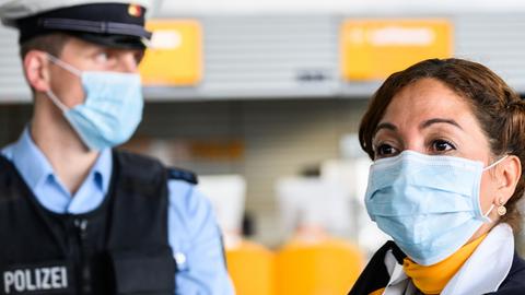 Ein Polizist und eine Polizistin mit OP-Masken in einer Flughafenhalle.