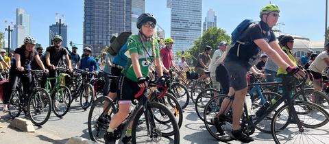 Teilnehmer der Fahrrad-Demonstration in Frankfurt fahren auf einer Straße, im Hintergrund sind die Banekentürme zu sehen