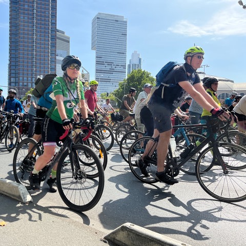 Teilnehmer der Fahrrad-Demonstration in Frankfurt fahren auf einer Straße, im Hintergrund sind die Banekentürme zu sehen