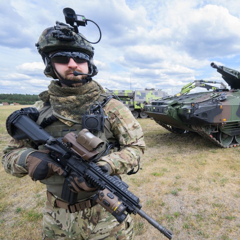 Der Schützenpanzer Puma auf dem Rheinmetall-Werksgelände in Unterlüß, davor steht ein Mann in Soldatenuniform und mit Maschinengewehr