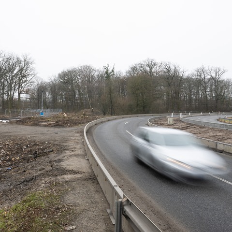 Ein Auto fährt auf der A66 an der Stelle vorbei, an der die Autobahn durch den Riederwaldtunnel unter dem Fechenheimer Wald erweitert werden soll. 