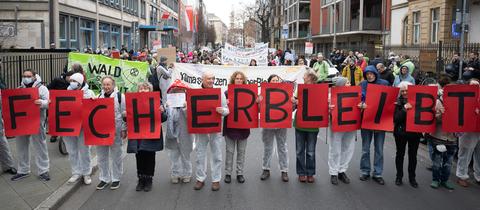 Teilnehmer halten während einer Demonstration Schilder hoch, auf denen "Fecher bleibt" steht.