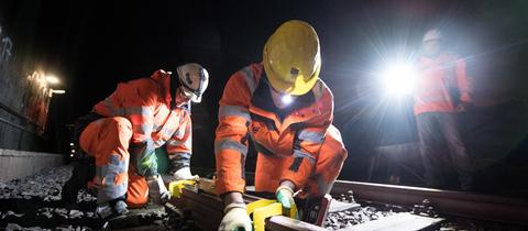 Arbeiter schleifen eine Schiene im Tunnel.