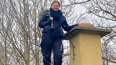 Schornsteinfeger-Azubine Hannah Beck steht auf einem Hausdach