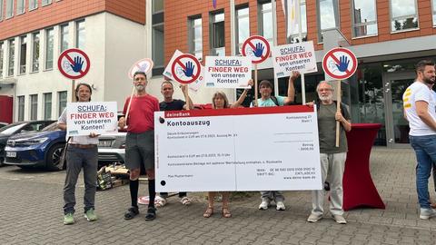 Protest von Aktivistinnen in Wiesbaden mit riesigem Kontoauszug, auf ihren Schildern steht: "Finger weg von unseren Konten!" 