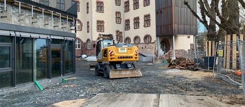 Baustellenfahrzeuge im Innenhof einer Schule.