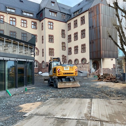 Baustellenfahrzeuge im Innenhof einer Schule.