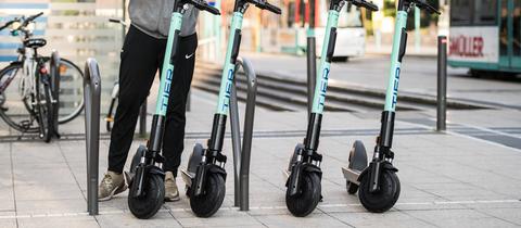 E-Tretroller in Frankfurt - ein Mann entsperrt einen von vier Rollern mit seinem Smartphone.