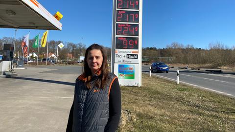 Die Betreiberin einer Tankstelle in Dieburg steht vor der Preistafel.
