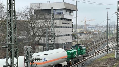 Ein grüner Güterzug rollt an einem grauen Gebäude vorbei