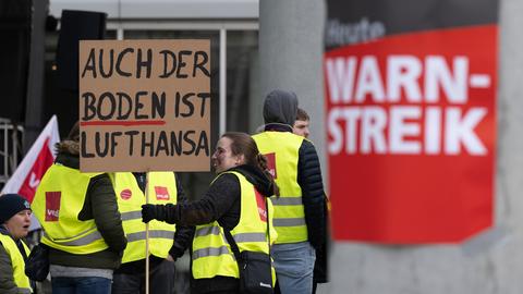 "Auch der Boden ist Lufthansa" steht auf einem Plakat, mit dem sich eine Frau am Streik beteiligt.