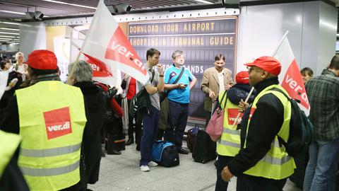 Pasażerowie czekają na lotnisku we Frankfurcie, gdy przechodzą obok nich protestujący członkowie Verdiego.