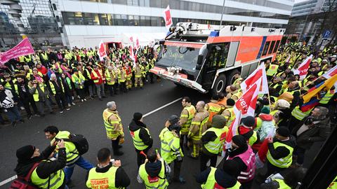 Streikende mit Verdi-Fahnen und Löschfahrzeug am Frankfurter Flughafen