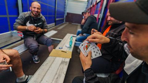 Streikende Fahrer sitzen in einem Lkw-Auflieger und spielen Karten. 