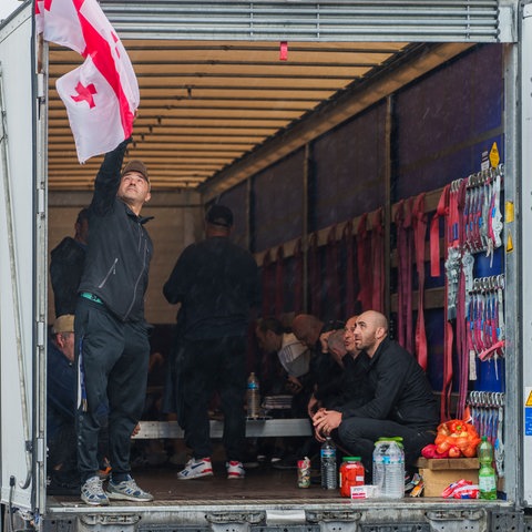 Ein streikender Fahrer hängt eine georgische Nationalflagge an einem Lkw-Auflieger auf.