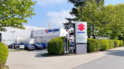 Einfahrt in ein Gewerbegebäudekomplex. An der Grenze eine Stele mit dem Suzuki-Logo.