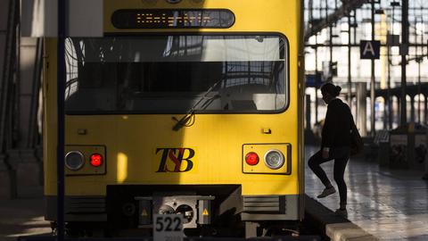 Ein gelber Zug der Taunusbahn steht am Prellbock im Frankfurter Hauptbahnhof. Rechts davon ist die Silouette einer Frau zu erkennen, die in die Bahn einsteigt.