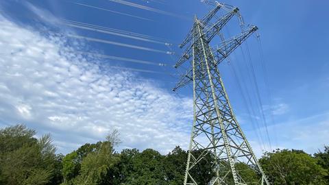 Ein Strommast vor blauem Himmel.