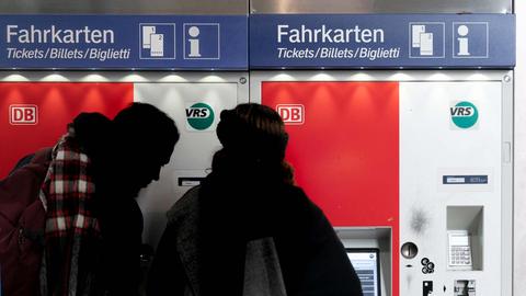 Zwei Menschen stehen vor einem Ticketautomat