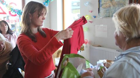 Eine Frau hält ein rotes T-Shirt prüfend hoch.