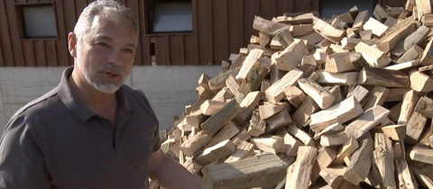 Niels Klahold, Brennholz-Produzent und Förster, steht vor einem Stapel Holzschaite.