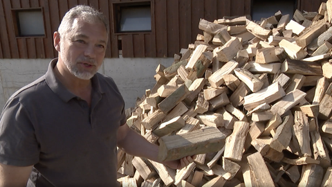 Niels Klahold, Brennholz-Produzent und Förster, steht vor einem Stapel Holzschaite.