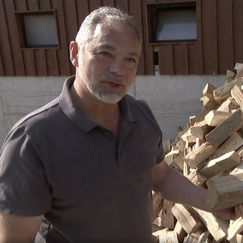 Niels Klahold, Brennholz-Produzent und Förster, steht vor einem Stapel Holzschaite.