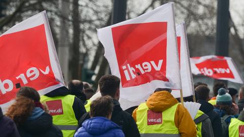 Streikende mit gelben Westen und weiß-roten Fahnen, auf denen "Verdi" steht.