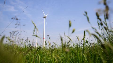 Zwei Windräder drehen sich auf einem Feld.