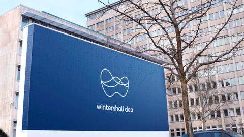 Ein Firmenschild mit dem blau-weißen Logo von Winterhall Dea steht vor dem Bürogebäude der Firma.