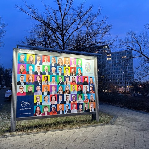 Ein Plakat mit Mitarbeiterinnen und Mitarbeitern von Wintershall Dea vor der Konzernzentrale in Kassel.