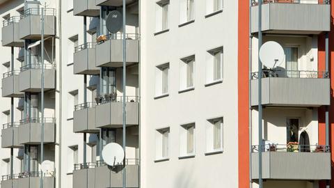 Ein Mietshaus mit mehreren Balkonen, auf denen zum Teil Satellitenschüsseln angebracht sind.