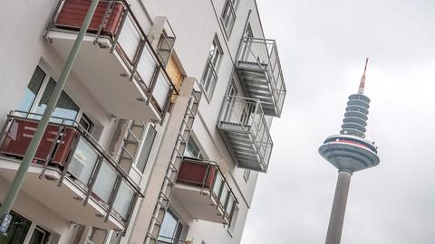 Foto eines neugebauten Mehrfamilienhauses aus der Froschpersepktive. Daneben in der Ferne der Fernsehturm.