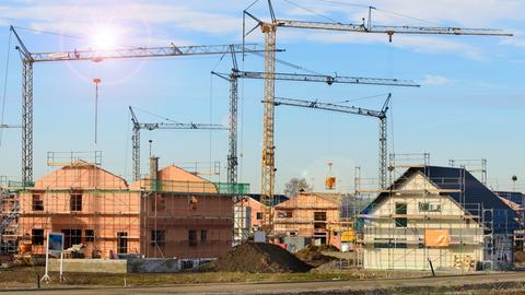 Neubaugebiet mit vielen Häusern im Rohbau und Baukräne