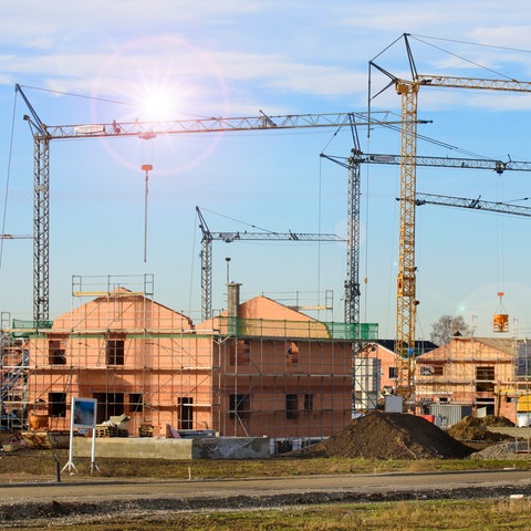 Neubaugebiet mit vielen Häusern im Rohbau und Baukräne